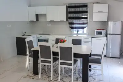 a kitchen with white cabinets and a table and chairs at Apartman Mona in Podgorica