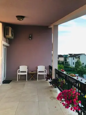 two chairs and a table on a balcony with flowers at Apartman Mona in Podgorica