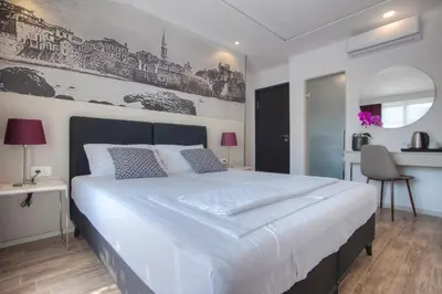 a bedroom with a large white bed and a desk at Casa Mia in Budva