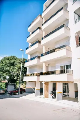 a white apartment building with a parking lot at Riva Luxury in Ulcinj