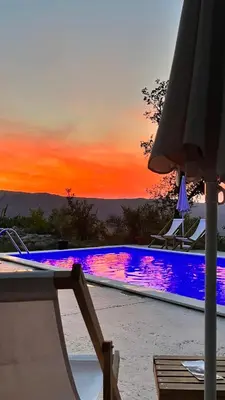 a swimming pool with a sunset in the background at Guesthouse P&A in Budva