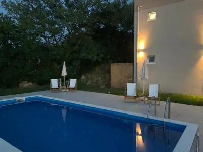 a swimming pool with chairs and a building at Guesthouse P&A in Budva