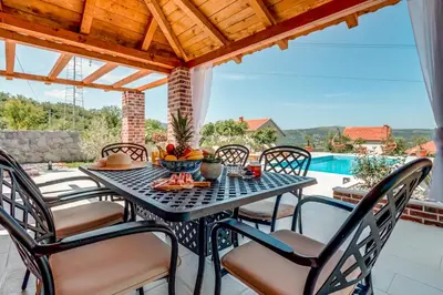a table and chairs on a patio with a pool at Villa Mina in Kotor