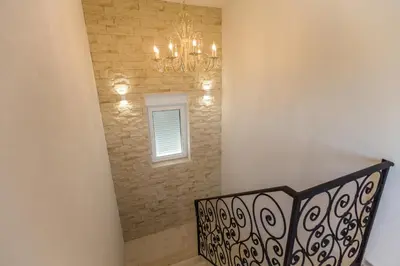 a staircase with a chandelier and a stone wall at Villa Mina in Kotor