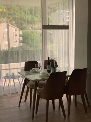 a dining room table with chairs and a bottle of wine at Butterfly Apartman in Rafailovici