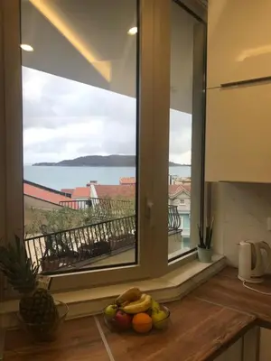 a kitchen with a view of the ocean from a window at Butterfly Apartman in Rafailovici