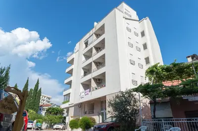 a tall white building with windows on a street at Apartman Natalia in Budva