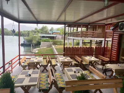 a restaurant with wooden tables and benches on the water at Ethno village Moraca - Skadar lake in Vranjina