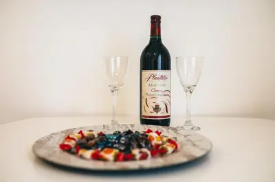 a plate of food with a bottle of wine and two glasses at Apartments Vojislav in Virpazar