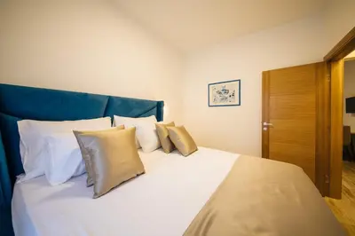a bed with white pillows and a blue head board at Apartments Vojislav in Virpazar