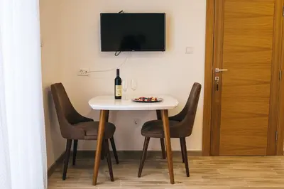 a table with a bottle of wine and two chairs at Apartments Vojislav in Virpazar