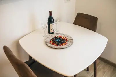 a white table with a bottle of wine and a cake at Apartments Vojislav in Virpazar