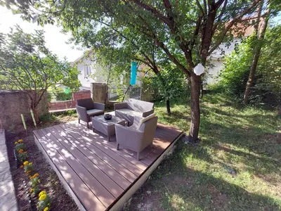 a wooden deck with two couches and a tree at Holiday Home Milanovic in Cetinje