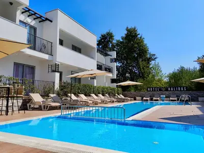 a swimming pool with chairs and umbrellas next to a building at Hotel Halibas in Ulcinj