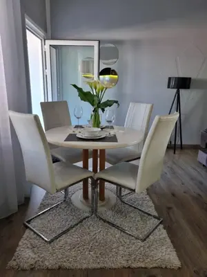 a dining room table with white chairs and a mirror at Harmony cozy home in Podgorica
