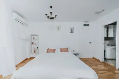 a white bedroom with a large bed and a bathroom at Apartments Trifunovic Old Town in Budva