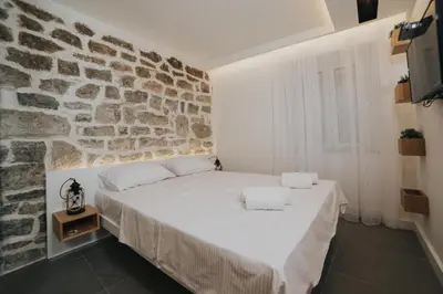a bedroom with a stone wall and a bed at Apartments Trifunovic Old Town in Budva