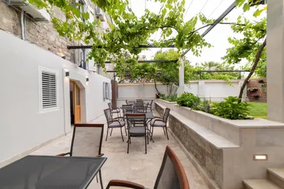 an outdoor patio with chairs and tables and trees at Apartments Trifunovic Old Town in Budva