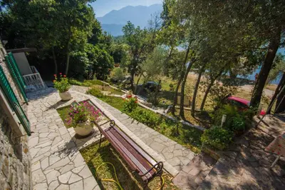 a bench in a garden with flowers and trees at Seaside Story in Tivat