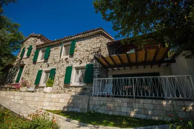an old stone house with green shutters and a porch at Seaside Story in Tivat