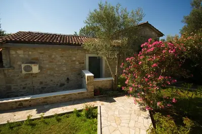 a stone house with a window and a bush with pink flowers at Seaside Story in Tivat