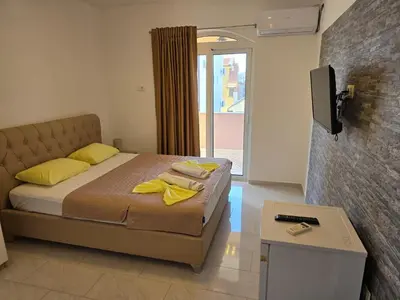 a bedroom with a bed and a tv on a wall at Vila Cattleya in Donji Štoj