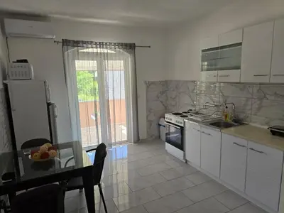 a kitchen with white cabinets and a table with a tableablish at Vila Cattleya in Donji Štoj