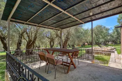 a wooden table and chairs on a balcony with trees at Stonehouse in Olives in Ulcinj