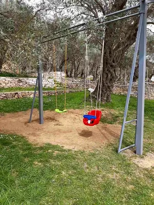 a playground with two swings in a park at Stonehouse in Olives in Ulcinj