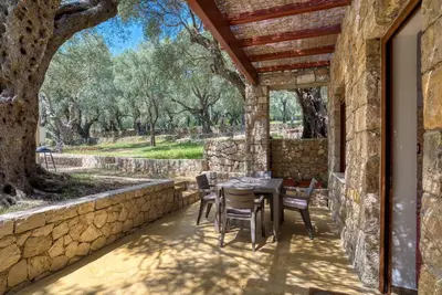 a patio with a table and chairs and a stone wall at Stonehouse in Olives in Ulcinj