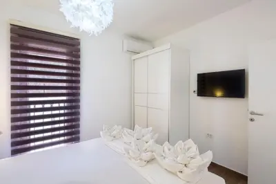 a white bedroom with a bed and a tv at Villa Lazy Hill in Budva