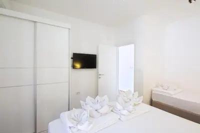 a white bedroom with white flowers on two beds at Villa Lazy Hill in Budva