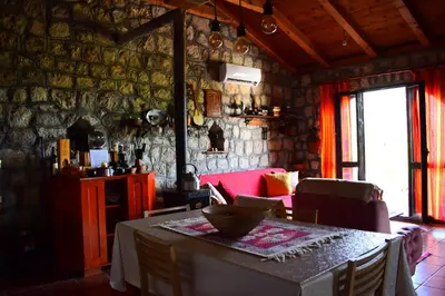 a dining room with a table and a red couch at Rent House Orahovo in Virpazar