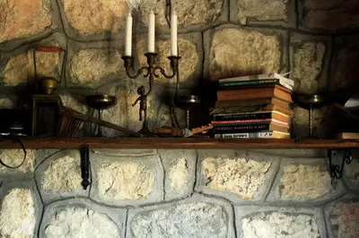 a shelf with books and candles on a stone wall at Rent House Orahovo in Virpazar