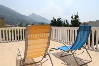 two chairs sitting on a balcony with mountains in the background at Vila AKI-KA in Sutomore