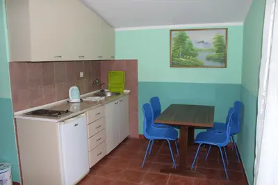 a kitchen with a table and blue chairs at Vila AKI-KA in Sutomore