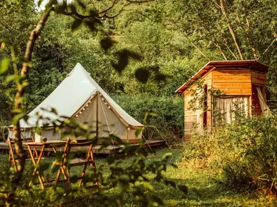 a tent and a wooden house in the woods at Hoopoe Glamping in Virpazar