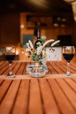 two glasses of wine and a vase of flowers on a table at Hoopoe Glamping in Virpazar
