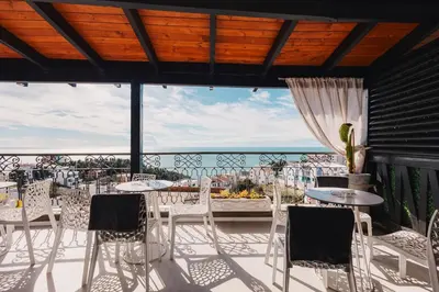 a patio with tables and chairs and a view of the ocean at Padam Hotel & SPA in Ulcinj