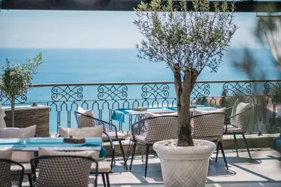 a patio with tables and chairs and a tree in a vase at Padam Hotel & SPA in Ulcinj