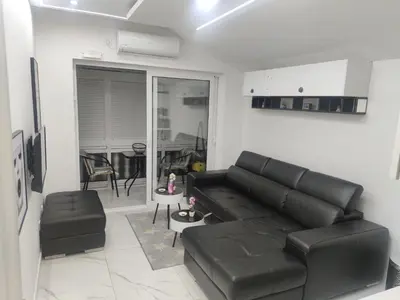 a living room with a black leather couch and a table at Studio 033 in Budva