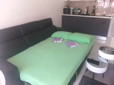 a green bed in a room with a kitchen at Studio 033 in Budva