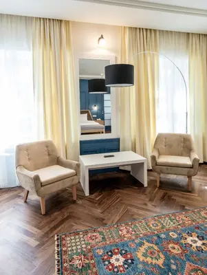a living room with two chairs and a table and a bed at Hotel Gradska Cetinje in Cetinje
