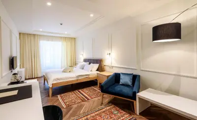 a hotel room with a bed and a blue chair at Hotel Gradska Cetinje in Cetinje