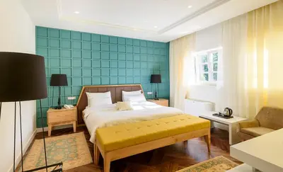 a bedroom with a bed and a couch and a chair at Hotel Gradska Cetinje in Cetinje