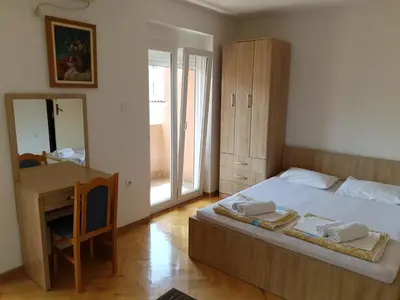a bedroom with a bed and a desk and a mirror at Apartment Senka in Budva