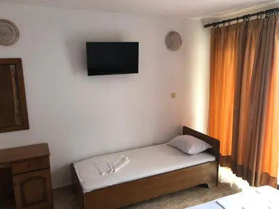 a room with a bed and a television on the wall at Apartments Toni in Ulcinj