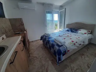 a bedroom with a bed and a sink and a window at Đuričić Apartmani in Budva