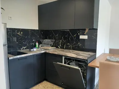 a kitchen with black cabinets and a sink at Đuričić Apartmani in Budva