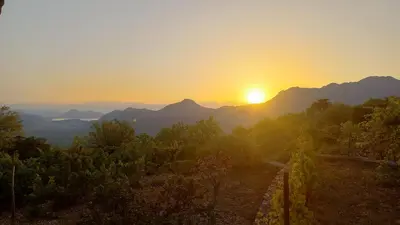 a sunset over a mountain range with the sun setting at Banjo Rustic House Lake view in Virpazar